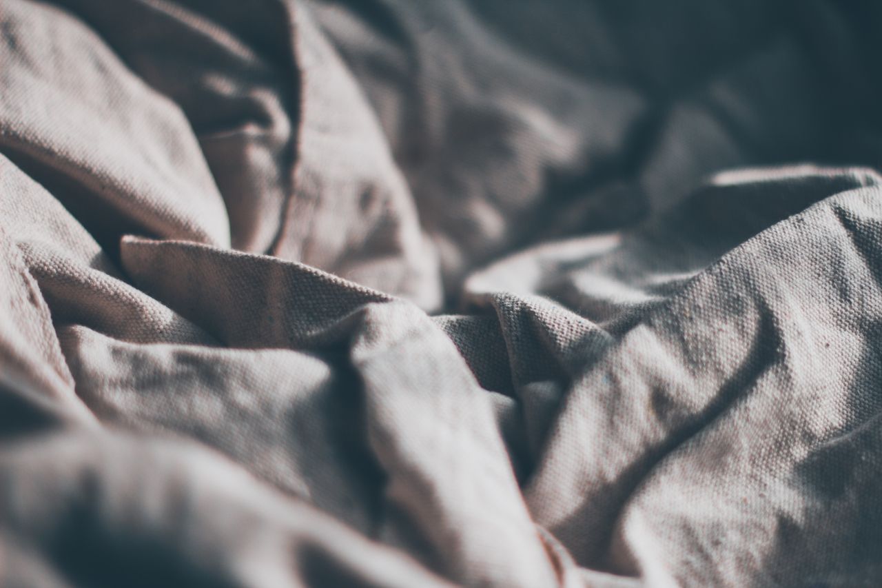 Close-up of creased soft linen fabric, emphasizing texture and natural tones.