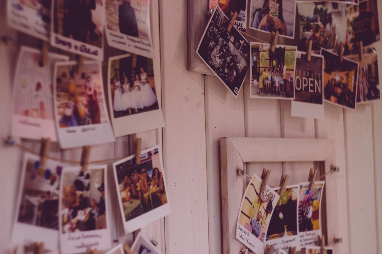Offerings Collection of vintage Polaroid photos clipped to a wooden wall indoors.