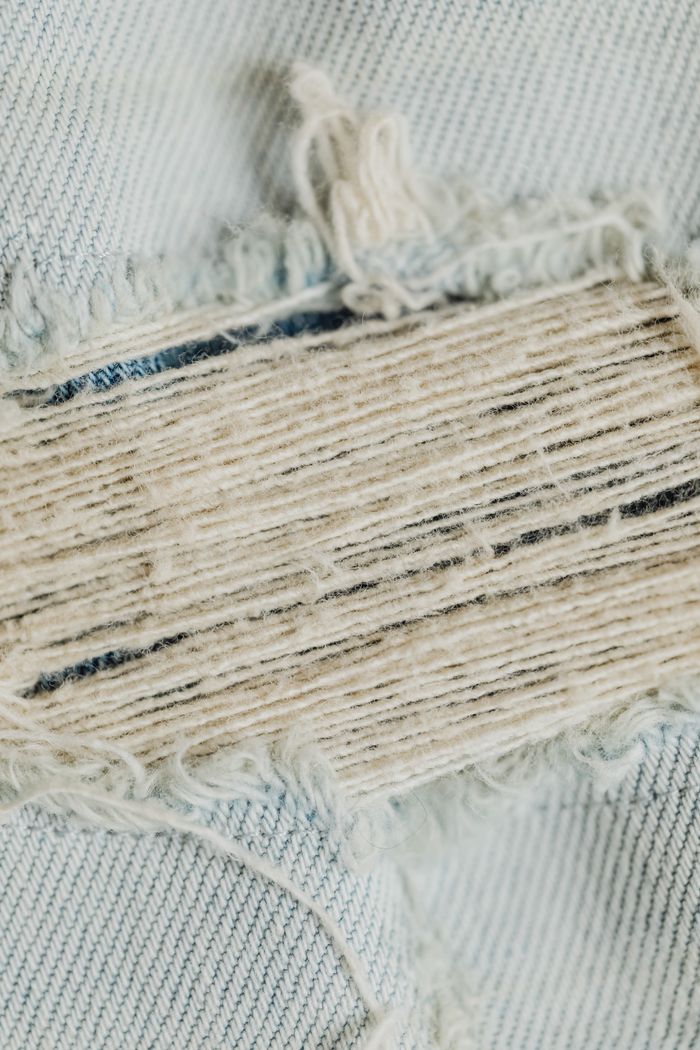 A detailed close-up view of a ripped denim fabric showcasing the intricate threads and texture.