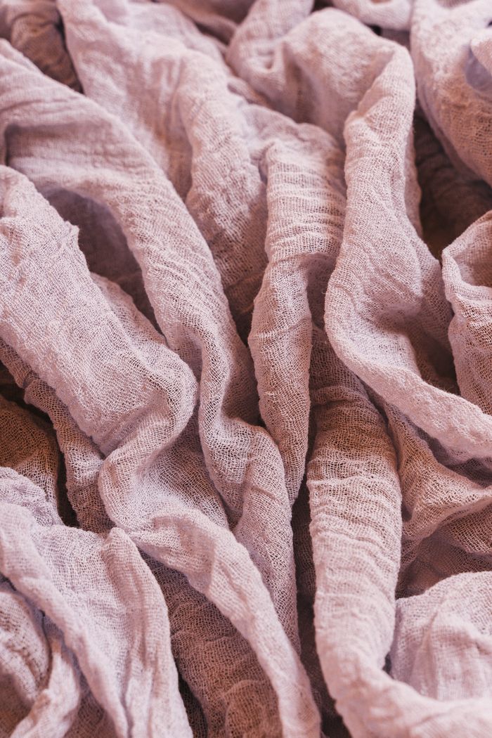 Close-up of crinkled purple linen fabric showcasing texture and folds. Ideal for design and textile concepts.